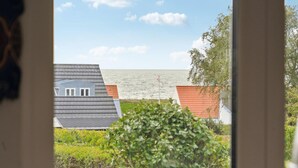 A coastal view with a house and a red-roofed building, a weather vane, and a body of water. - 3 bedroom gorgeous home in Assens (Assens)