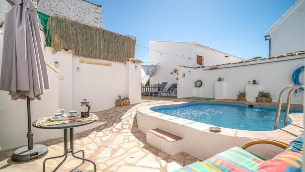 Un área de piscina con jacuzzi, sillones de descanso y una mesa pequeña con cafetera.