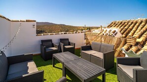 Una terraza en la azotea con mobiliario de mimbre, vistas a campos escalonados y cielo despejado.