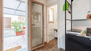 Une cuisine moderne avec un plan de travail noir, une porte vitrée donnant sur un patio et un porte-ustensiles suspendu de couleur verte.