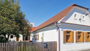 En vit byggnad med ett rött tegeltak, träpersienner och en skylt med siffran ’12’.