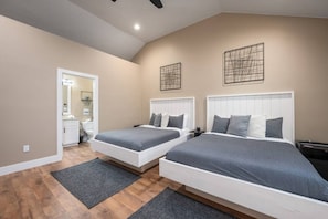 Une chambre avec deux lits, une salle de bain et un ventilateur de plafond.