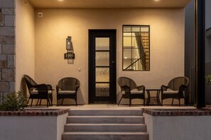 A front entrance with a black door, a staircase, and wicker chairs. - Gaming, Pool, Relaxing, and Memories are all made at After Dune Delight! (Hurricane)