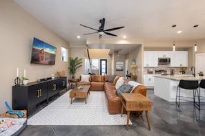A spacious living room with a leather sectional sofa, a black entertainment unit, and a ceiling fan.