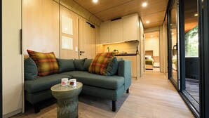 A modern living room with a sofa, a coffee table, and a kitchen area visible through an open door. - Forest Lodges (Betws-Y-Coed)