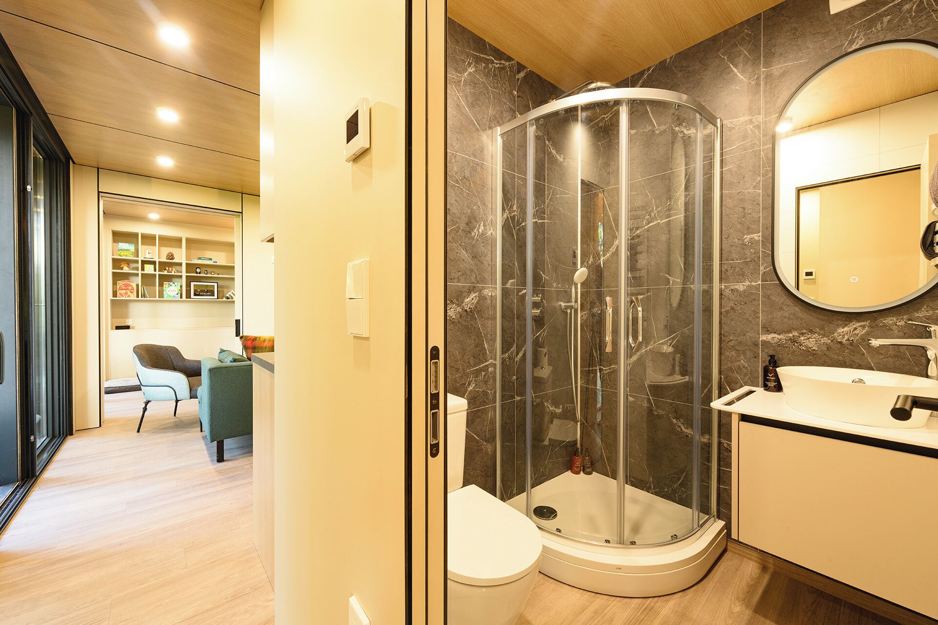 Un bagno moderno con cabina doccia in vetro, un water bianco e un mobile lavabo con specchio.