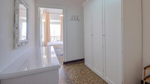Een gang met een witte inbouwkast, een spiegel en een deur naar een balkon.