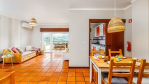Eine moderne Küche mit Holzausstattung, einem Esstisch für zwei Personen und einem großen Fenster mit Blick auf einen Garten.