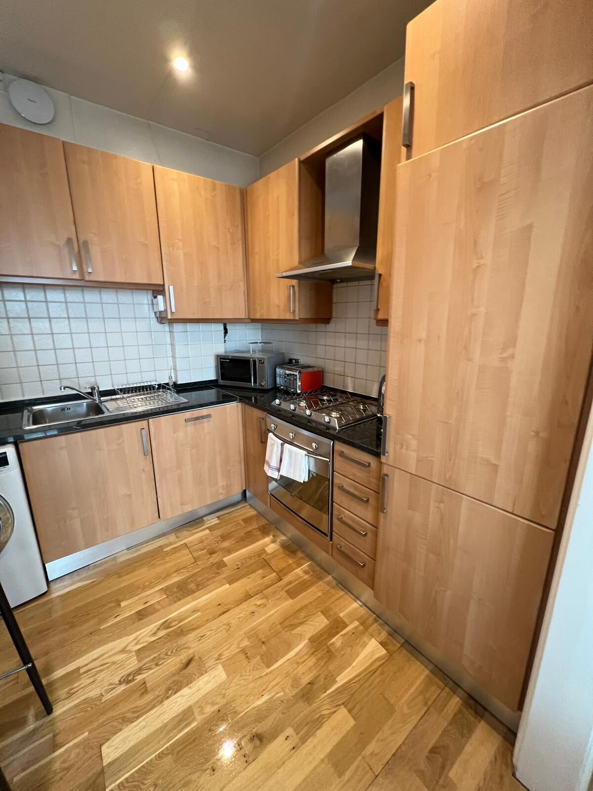 Una cocina con armarios de madera, microondas, tostadora, estufa y lavavajillas.