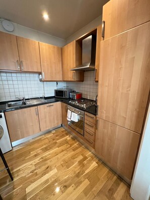 A kitchen with wooden cabinets, a microwave, a toaster, a stove, and a dishwasher.