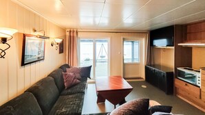 Un salon confortable avec un canapé, une table en bois et un coin cuisine équipé d’une cuisinière et d’un four à micro-ondes.