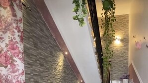 A staircase with a stone wall, potted plants, and a floral curtain. - B&B Le Onde del Mare (San Vito Lo Capo)