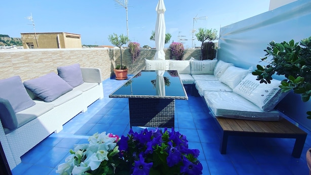 A rooftop terrace with a glass-top table, white sofas, and potted plants. - B&B Le Onde del Mare (San Vito Lo Capo)