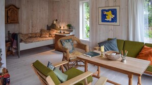 Ein gemütliches Zimmer mit einem Bett, einem Korbsessel, einem Holztisch und einem Sofa.