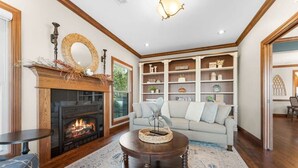 Ein Wohnzimmer mit Kamin, einer Couch, einem Couchtisch und einem Bücherregal.