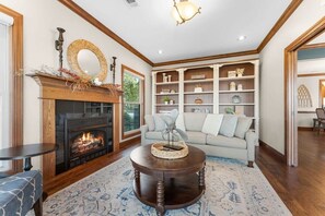 A living room with a fireplace, a sofa, a coffee table, and a bookshelf.