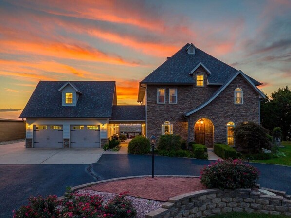 A two-story house with a garage, stone exterior, and a driveway leading to the entrance.