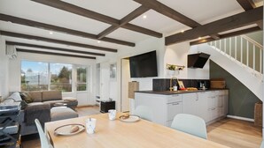 Eine moderne Küche mit Flachbildfernseher, Holzbalken und einem Essbereich mit Tisch und Stühlen.