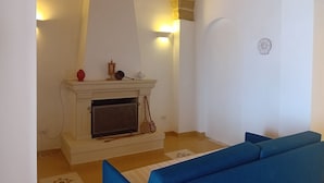 Quarto com lareira, um sofá azul e um arco de pedra.