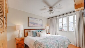 A bedroom with a bed, nightstands, a ceiling fan, a window with curtains, and a painting on the wall. - Steps to Ocean and Boardwalk, Parking, Outdoor dining! (San Diego)