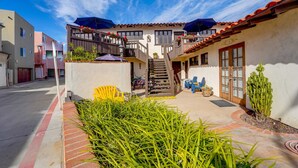 A courtyard with a staircase leading to a balcony, surrounded by buildings with balconies and outdoor seating. - Steps to Ocean and Boardwalk, Parking, Outdoor dining! (San Diego)