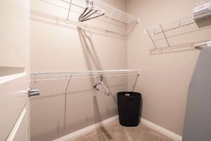 A corner of a room with a white wall, a grey door, and a black trash bin. - Amazing Apartment Along the River (Columbus)