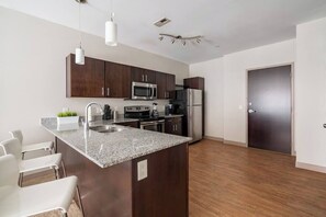 A modern kitchen with dark wood cabinets, stainless steel appliances, and a granite countertop island. - Downtown Apt in the Heart of Columbus (Columbus)