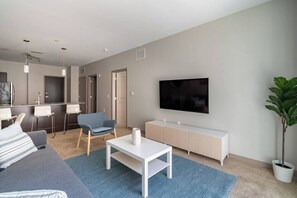 Uma sala de estar moderna com uma televisão de tela plana, um sofá, uma mesa de centro e um vaso de planta.