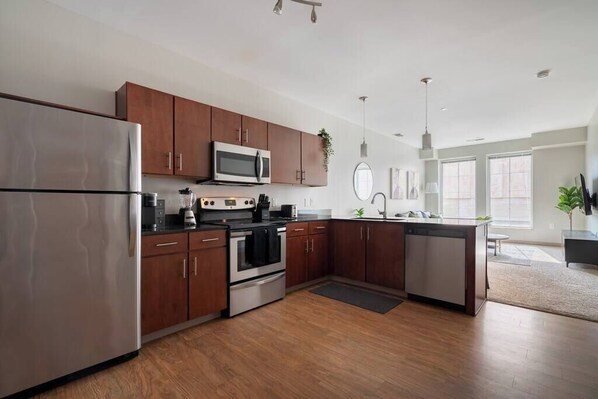A modern kitchen with stainless steel appliances, wooden cabinets, and a central island.