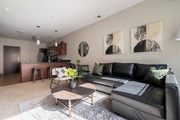 A modern living room with a sofa, coffee table, and artwork on the wall.