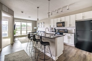 Una cocina moderna con armarios blancos, un refrigerador negro y una isla central con taburetes de bar.