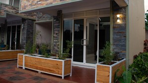 Een modern gebouw met een gevel van baksteen, grote glazen deuren en houten plantenbakken met beplanting.