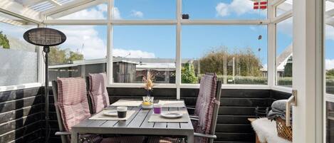 A conservatory with a table and chairs, large windows, and a flag.