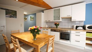 Una cocina moderna con armarios blancos, una mesa de comedor de madera y un florero con flores.