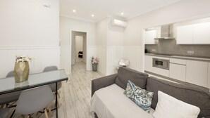 A compact living space with a kitchenette, a dining area, and a sofa with cushions. - Recaredo, Nº3- Apartment 2 bedrooms 2nd Floor (Sevilla)