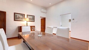 A dining area with a wooden table, white chairs, and framed artwork on the walls. - Apartment in Oltrarno area (Florence)