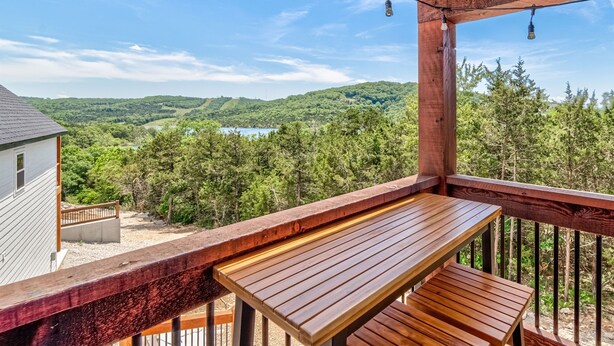 A wooden deck with a bench overlooking a forested landscape and a body of water. - Lake Access, Hot Tub, Pools, Paddleboard, Sleep 20 (Hollister)