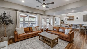 A spacious living room with a large sectional sofa, a coffee table, and a ceiling fan. - Lake Access, Hot Tub, Pools, Paddleboard, Sleep 20 (Hollister)