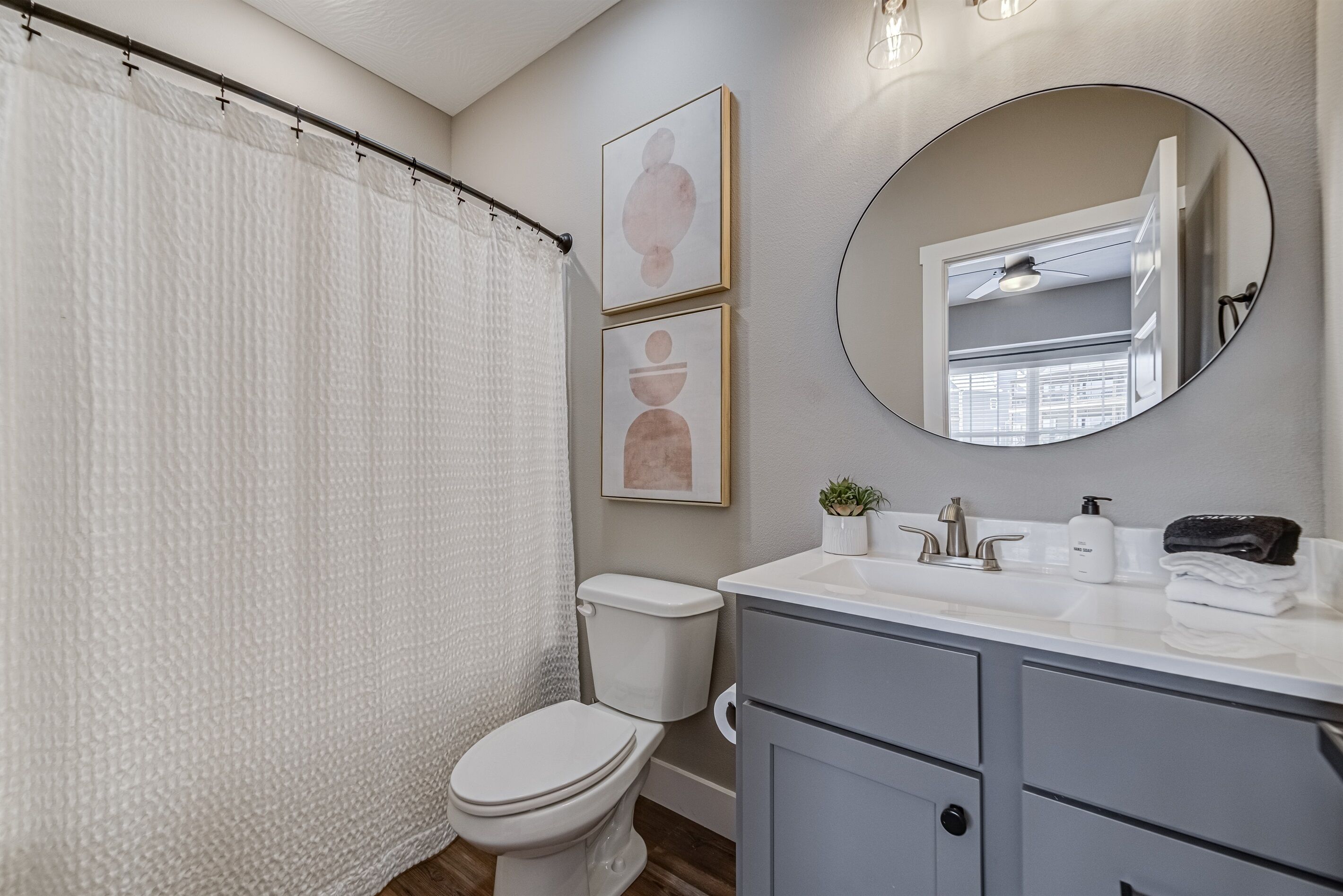 A bathroom with a toilet, a sink with a mirror, and a shower curtain.