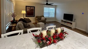 Un salon comprenant une table à manger, un canapé, un téléviseur et un ventilateur de plafond.