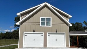 Un garage pour deux voitures, doté d’un toit en pente et d’une seule fenêtre située au-dessus des portes du garage.