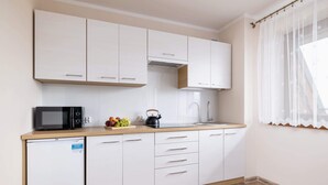 Una cocina moderna con armarios blancos, un microondas, un hervidor y un lavamanos.