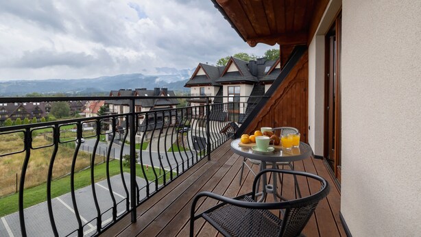 Un balcón con una mesa y sillas, con vistas a una calle y edificios.