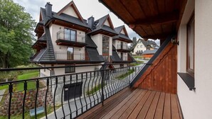 Une terrasse en bois avec une rambarde en métal, donnant sur un quartier résidentiel avec des maisons.
