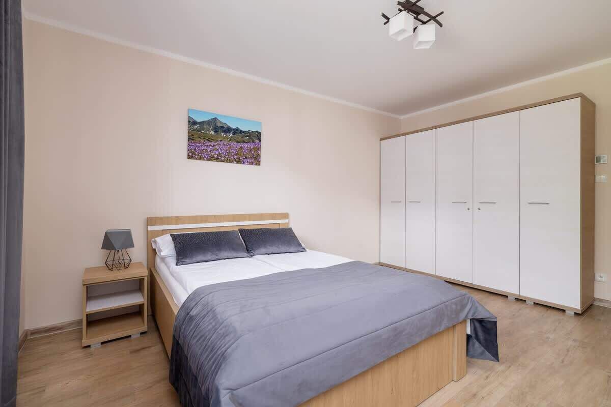 Ein Schlafzimmer mit Bett, Nachttisch, Kleiderschrank und einem an der Wand hängenden Bild.