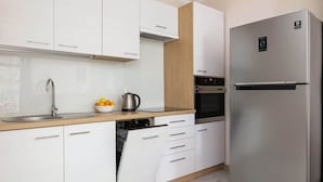 Une cuisine moderne avec des meubles blancs, un réfrigérateur en acier inoxydable et un lave-vaisselle.