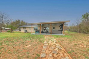 Ein modernes Haus mit überdachter Terrasse, Kiesweg und umzäunter Garten.