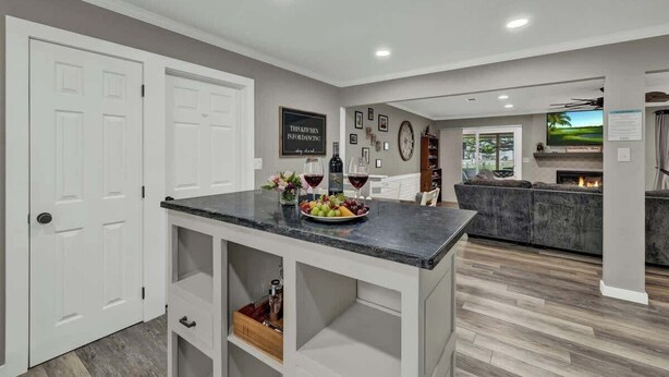 A modern kitchen with white cabinetry, a marble countertop, and a built-in wine rack.