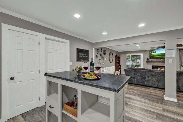 A modern kitchen with a marble countertop, white cabinetry, and a built-in wine rack.