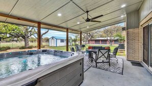 A covered patio with a hot tub, outdoor furniture, and a view of the backyard.